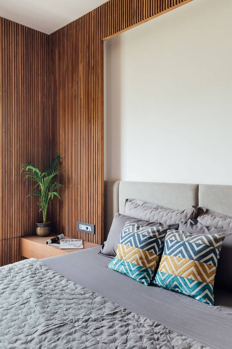 Phòng ngủ của bố mẹ được thiết kế sang trọng với bức tường gỗ ốp dọc bao quanh phía đầu giường cùng tông màu xám của đồ nội thất. Một chậu cây nhỏ đặt đầu giường đủ đem lại cảm giác bình yên cho căn phòng